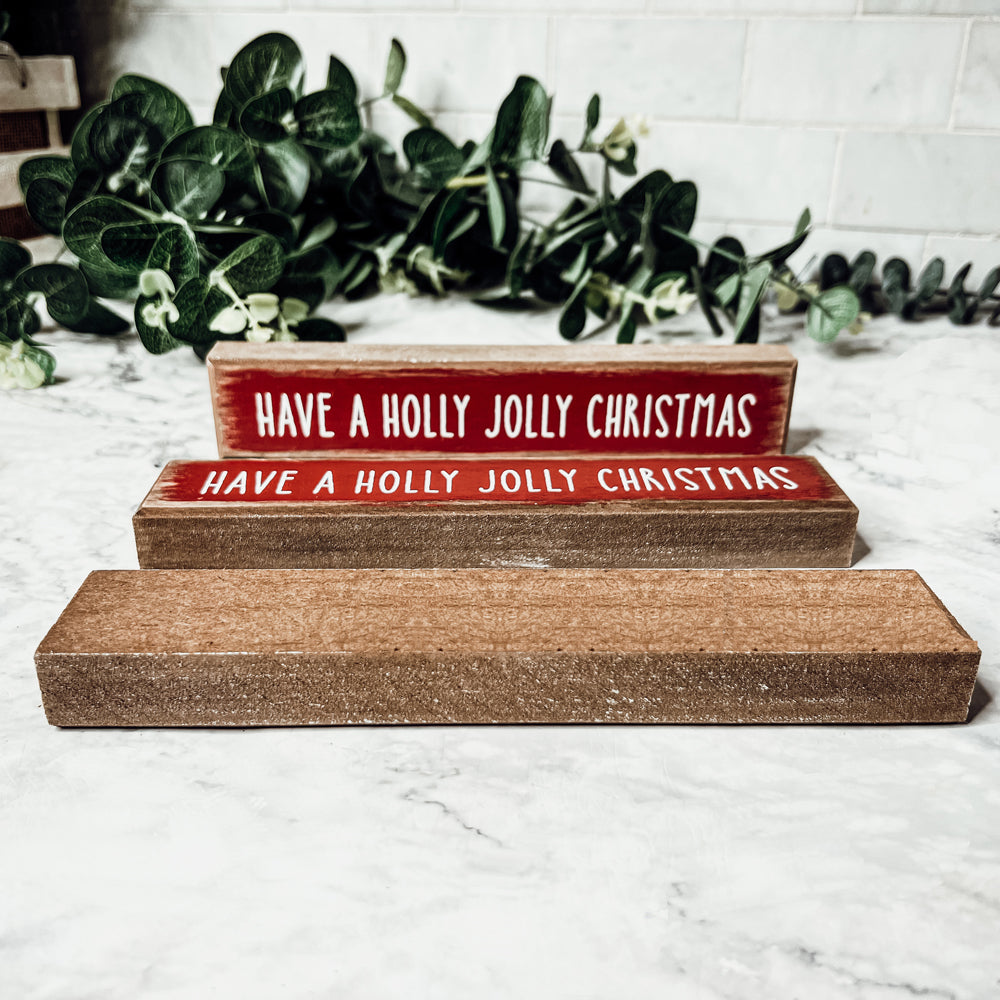 Holly Jolly Sitter Sign, a wooden block sign with festive lettering, perfect for holiday decor.