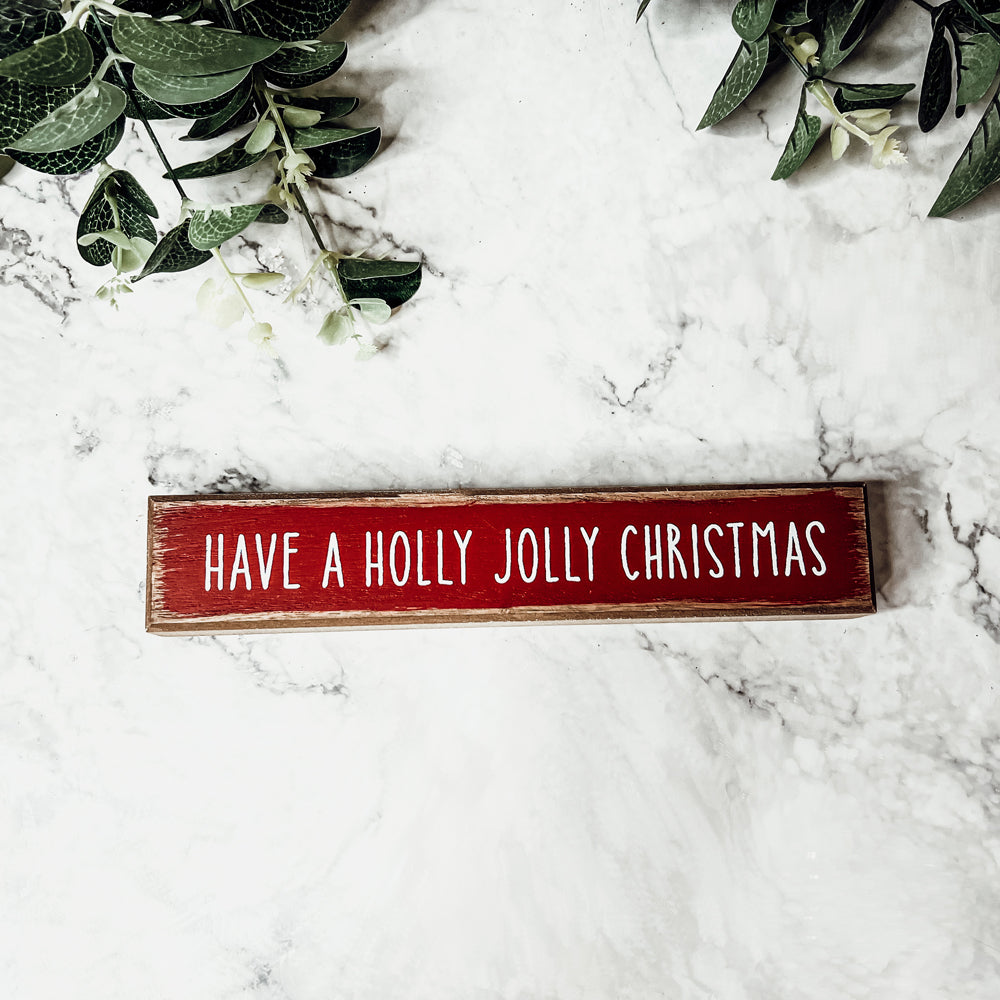 Holly Jolly Sitter Sign, a wooden block sign with festive lettering, perfect for holiday decor.