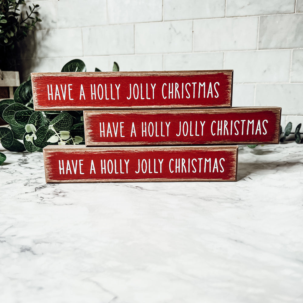 Holly Jolly Sitter Sign, a wooden block sign with festive lettering, perfect for holiday decor.