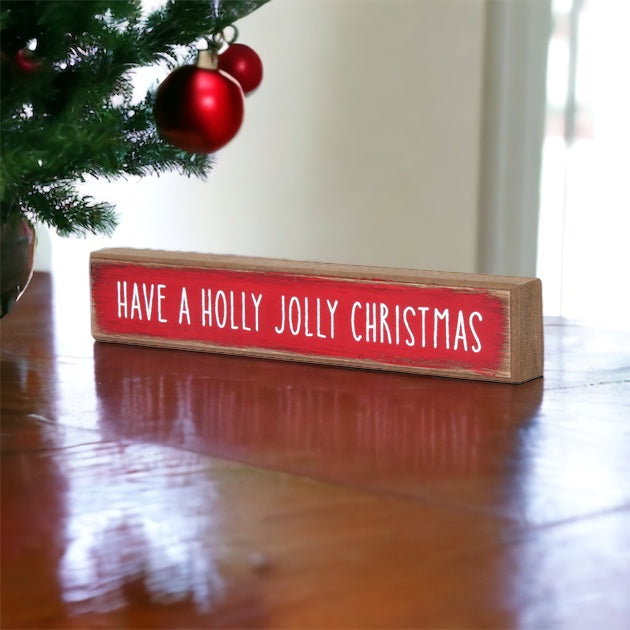 Holly Jolly Sitter Sign, a wooden block sign with festive lettering, perfect for holiday decor.