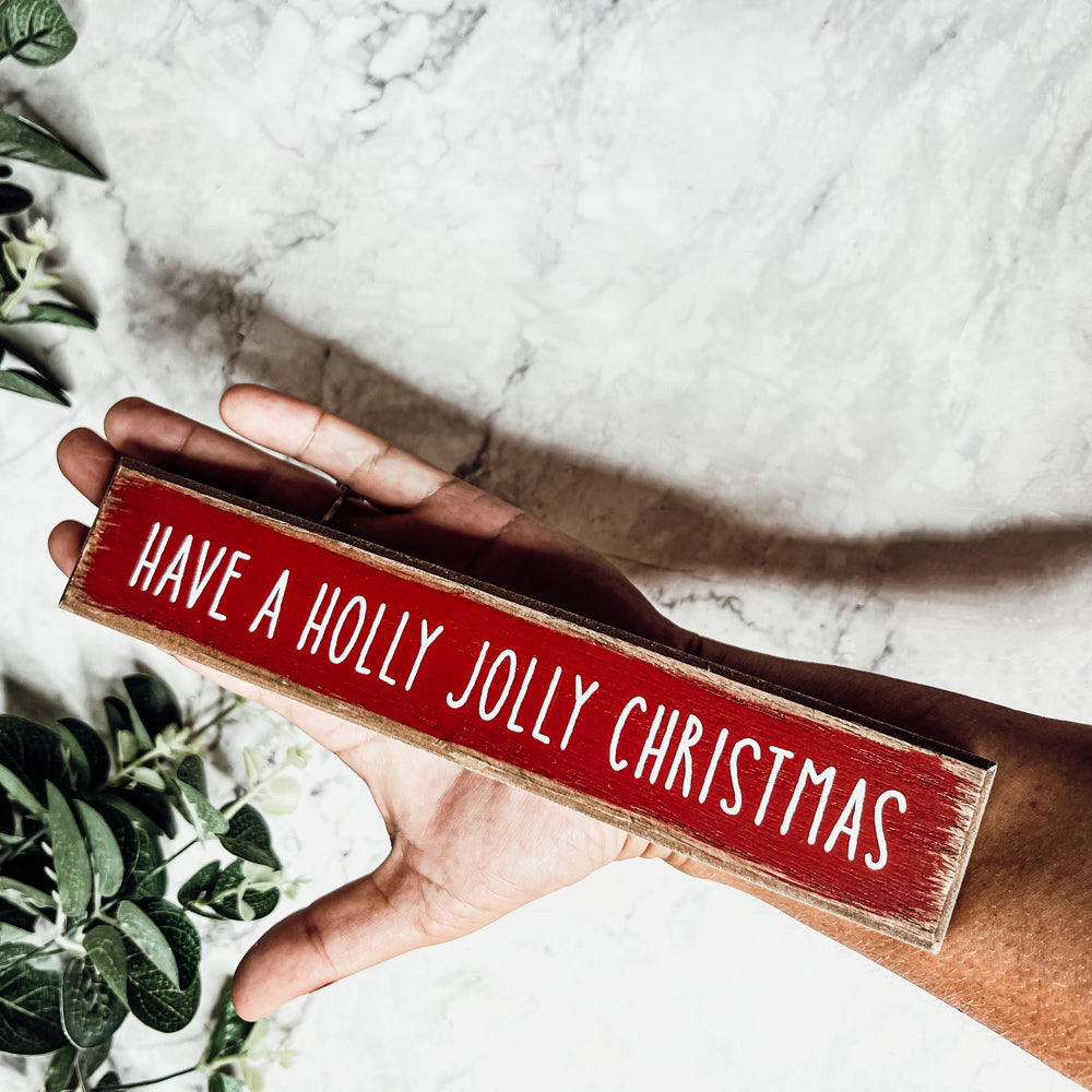 Holly Jolly Sitter Sign, a wooden block sign with festive lettering, perfect for holiday decor.