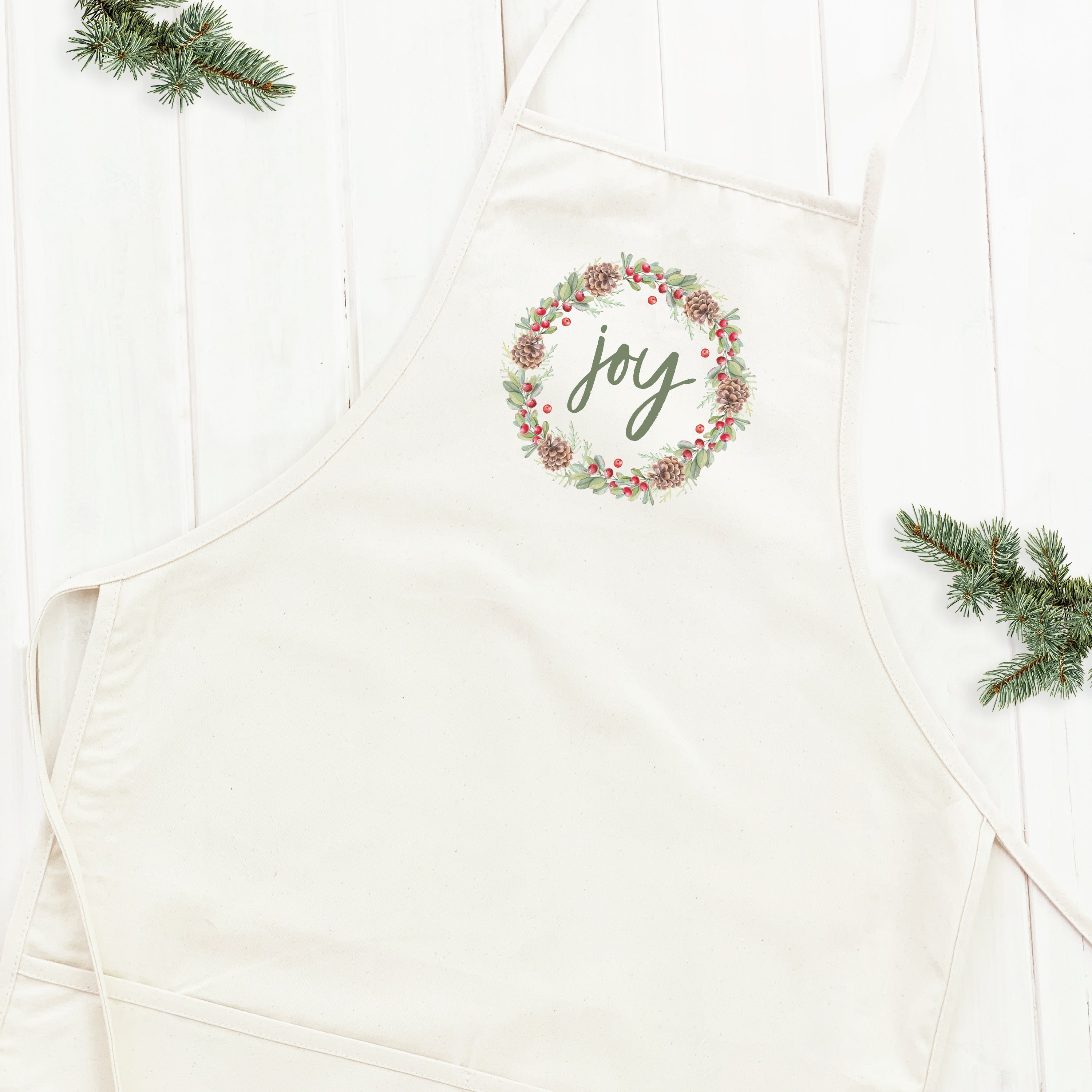 Joy Wreath Women's Apron featuring elegant design, adjustable neck, and divided front pocket, made from durable cotton canvas.