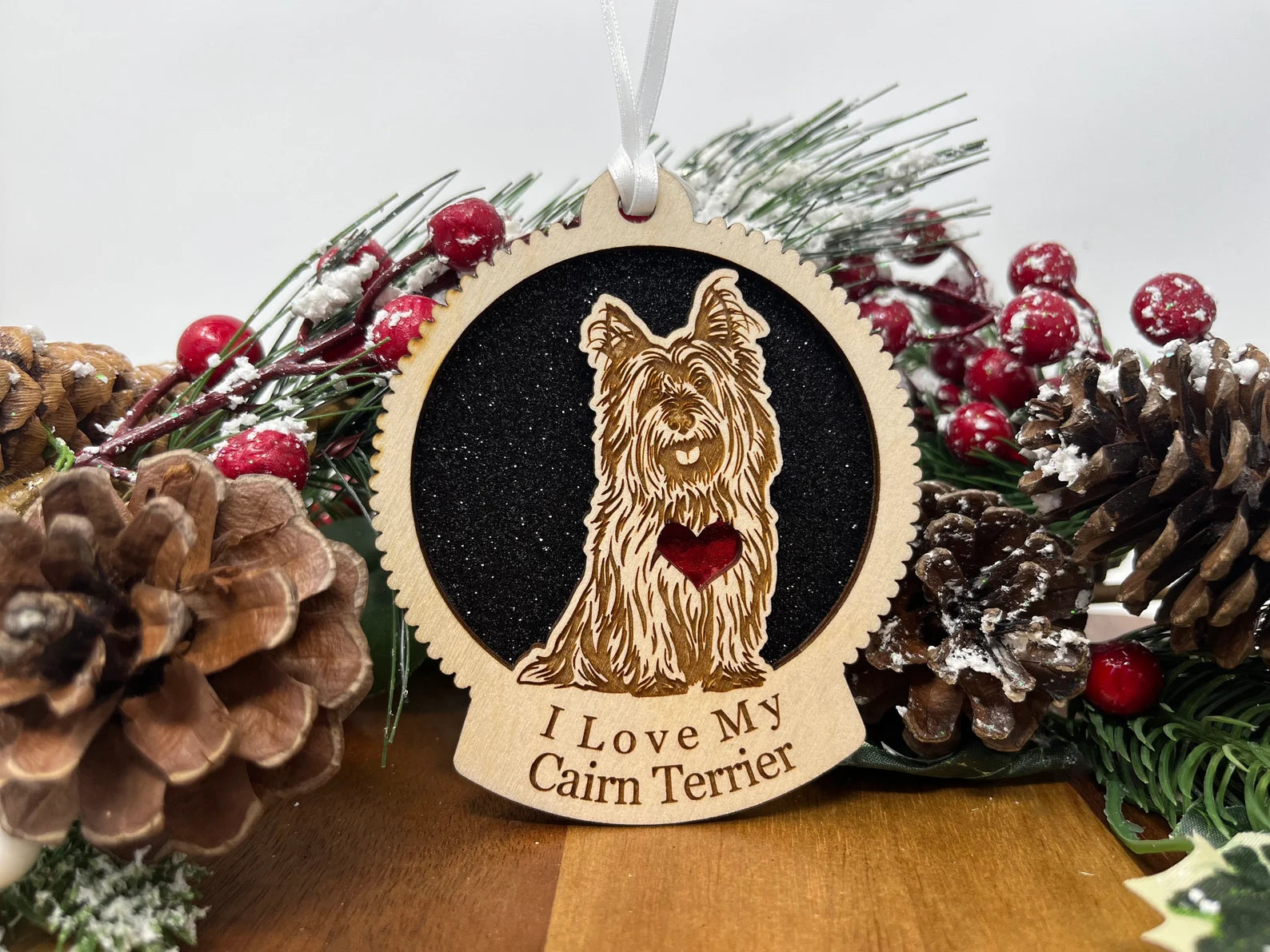 A beautifully crafted wooden ornament featuring a laser-cut silhouette of a Cairn Terrier, perfect for holiday decor.