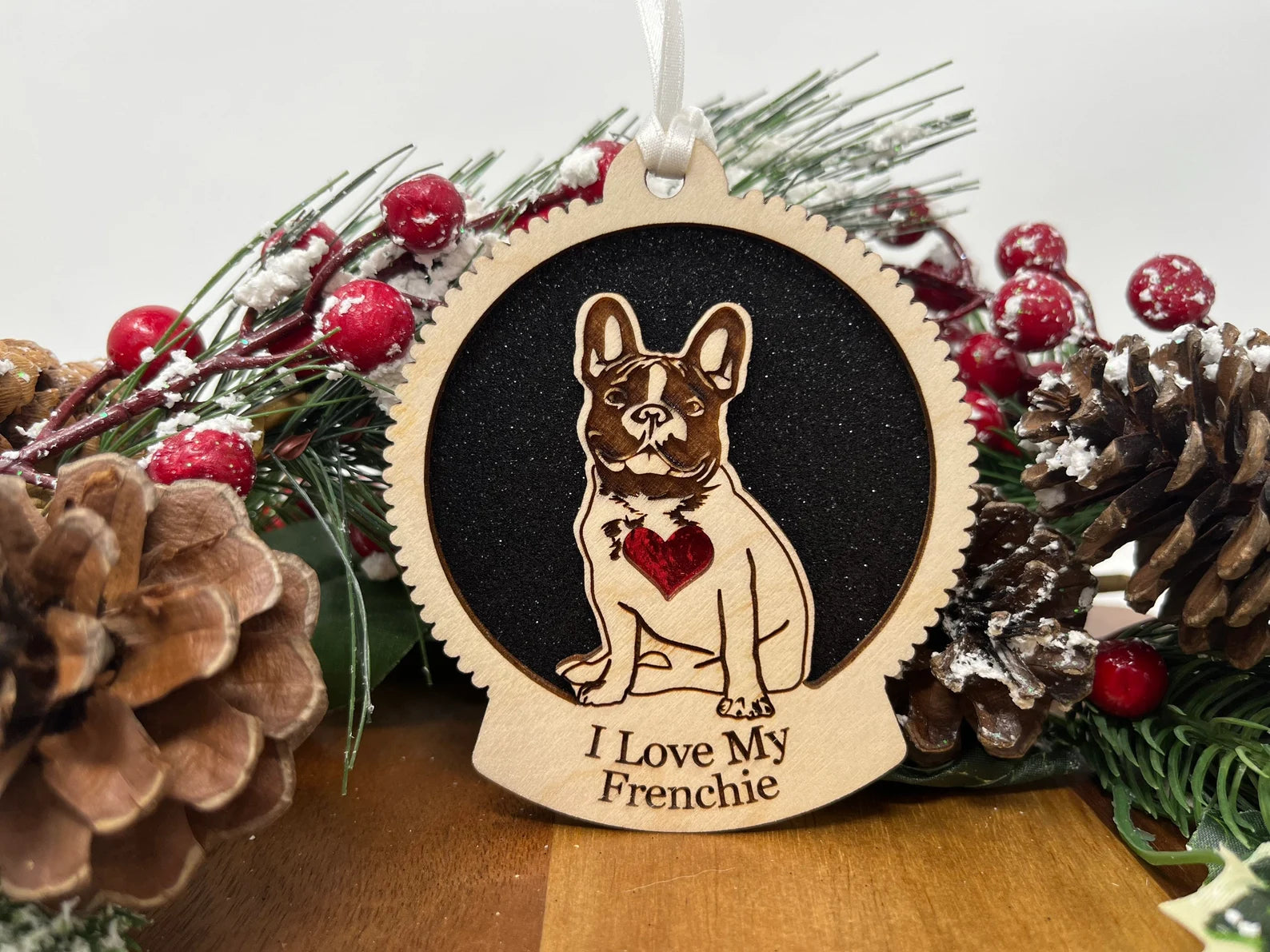 Love My Frenchie Christmas ornament made of laser cut Baltic Birch wood, featuring a silhouette of a French Bulldog, ready to hang with a ribbon.