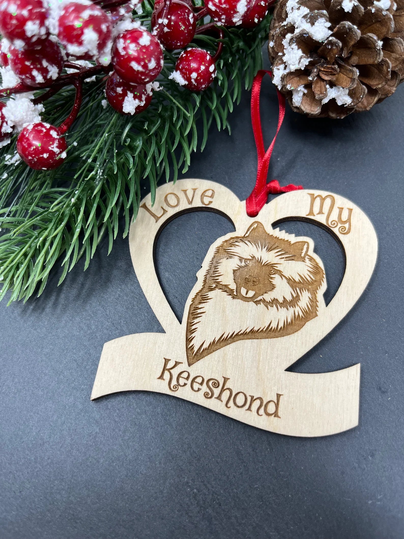 Laser engraved wooden ornament featuring a Keeshond, perfect for Christmas decoration.