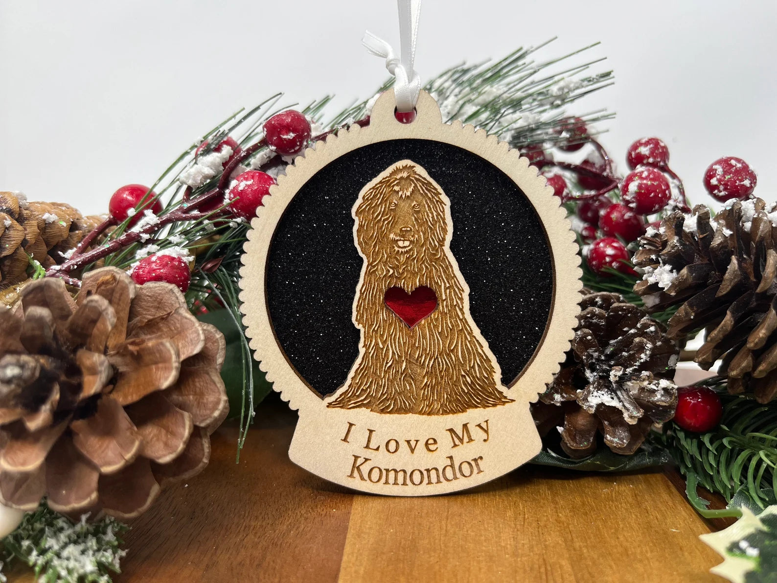 A beautifully crafted Love My Komondor ornament made from laser-cut Baltic Birch wood, featuring a silhouette of the Komondor dog, ready to hang with a ribbon.