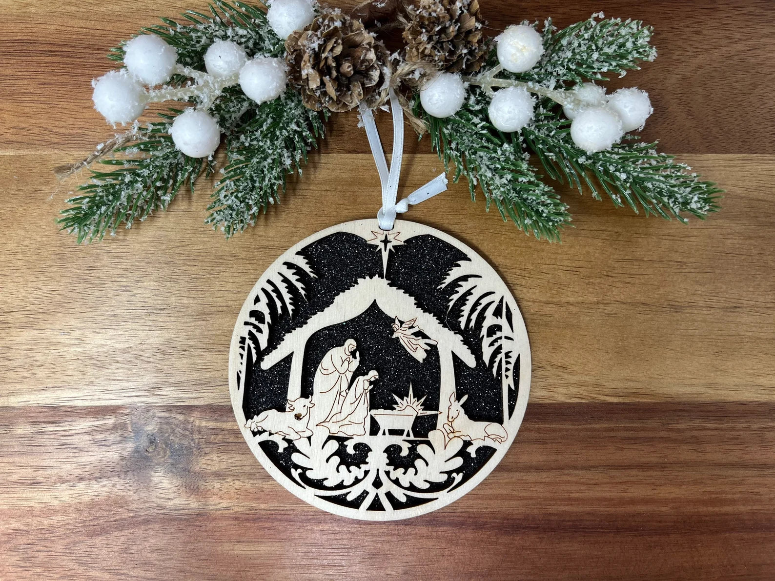 Elegant Nativity in Stable Round Ornament made from birch wood, featuring intricate cut design and ribbon for hanging.