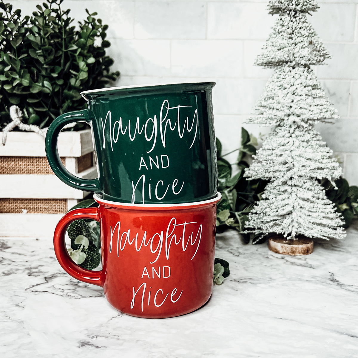 A vibrant Naughty & Nice Mug in red and green ceramic, featuring playful white lettering on both sides, perfect for coffee lovers.