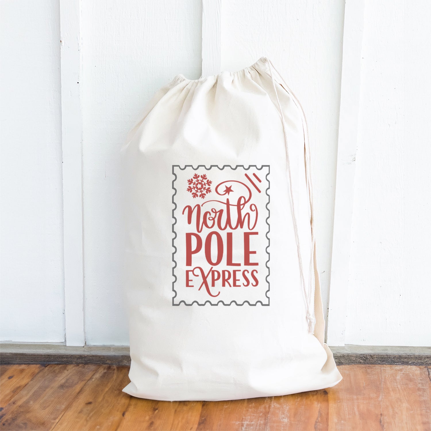 North Pole Express Santa Sack made of heavy-duty canvas with a drawstring closure, featuring festive designs and cotton webbing handle.