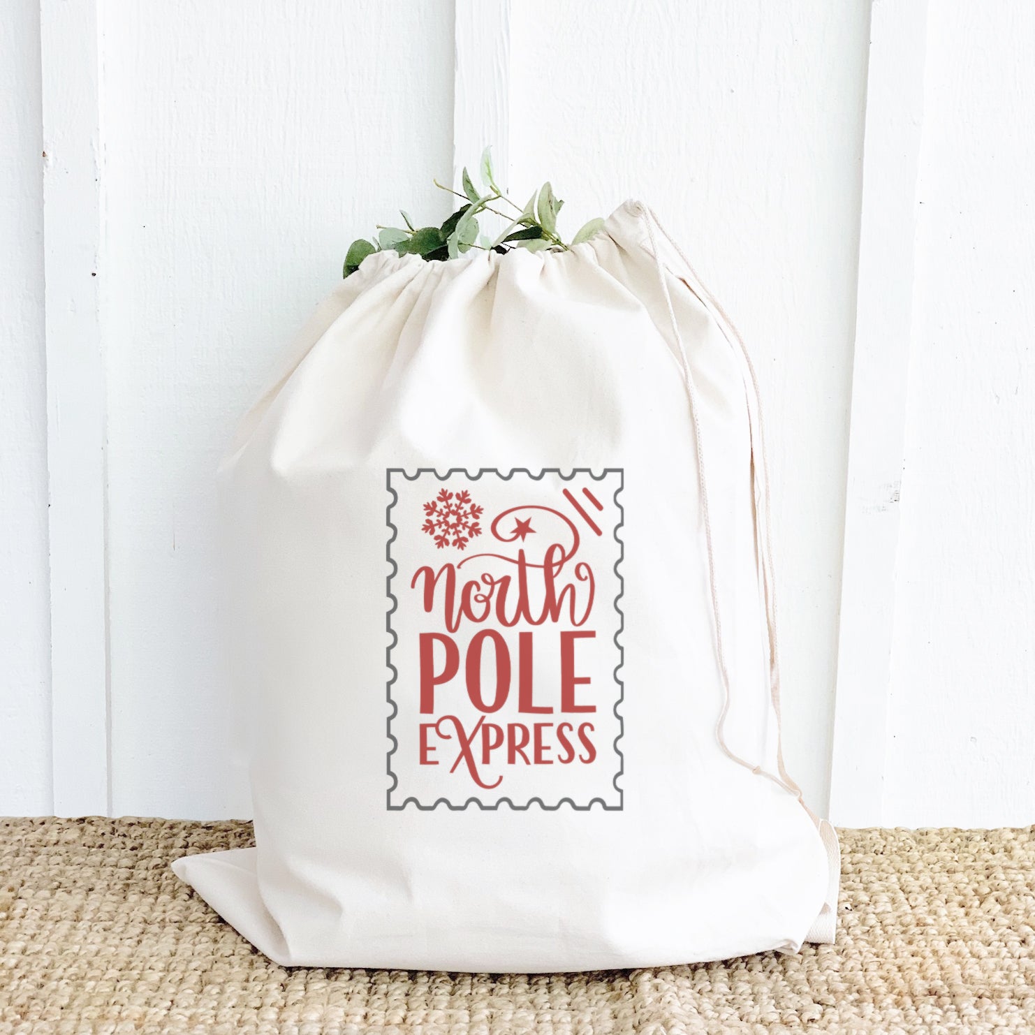 North Pole Express Santa Sack made of heavy-duty canvas with a drawstring closure, featuring festive designs and cotton webbing handle.