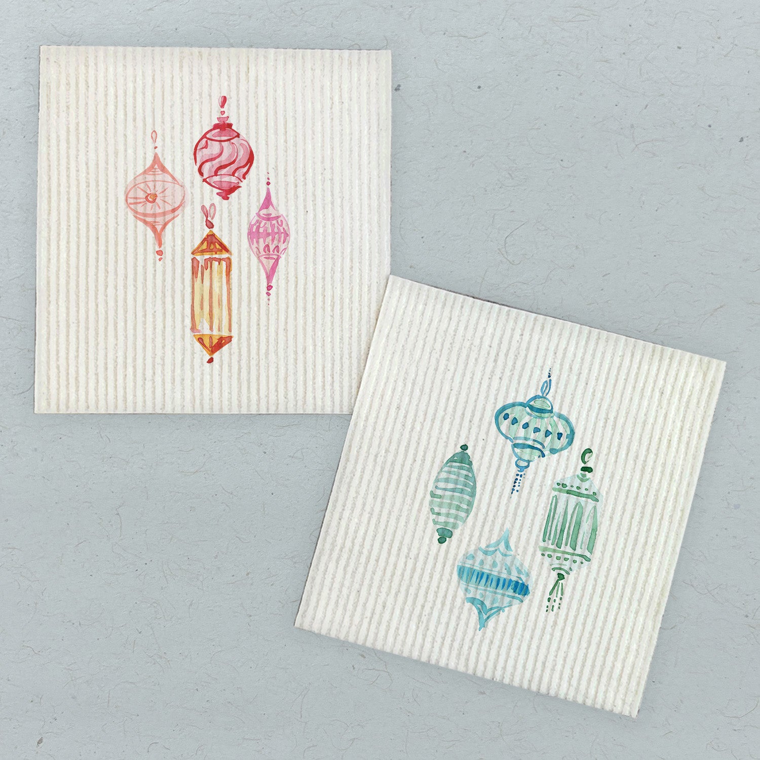 Two Swedish dish cloths featuring pink and blue ornament designs, made from eco-friendly materials.