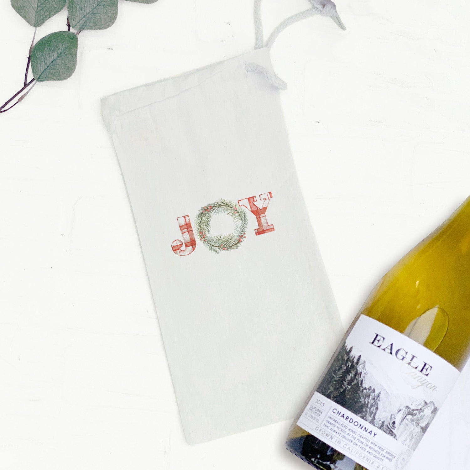 Plaid Joy Wreath Canvas Wine Bag featuring a festive plaid design with a drawstring closure, perfect for gifting wine.