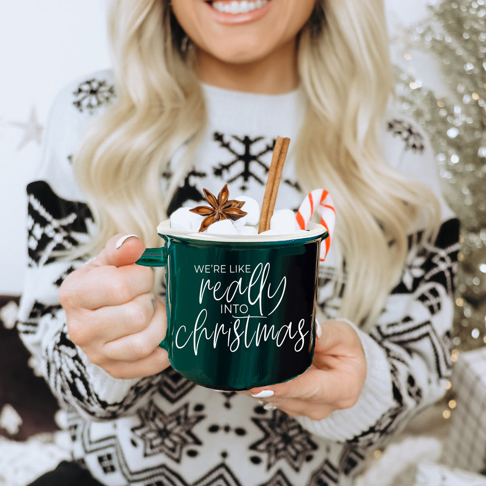 A vibrant red and green ceramic mug with white lettering, featuring a festive design on both sides, perfect for holiday drinks.