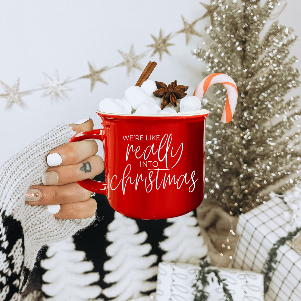 A vibrant red and green ceramic mug with white lettering, featuring a festive design on both sides, perfect for holiday drinks.