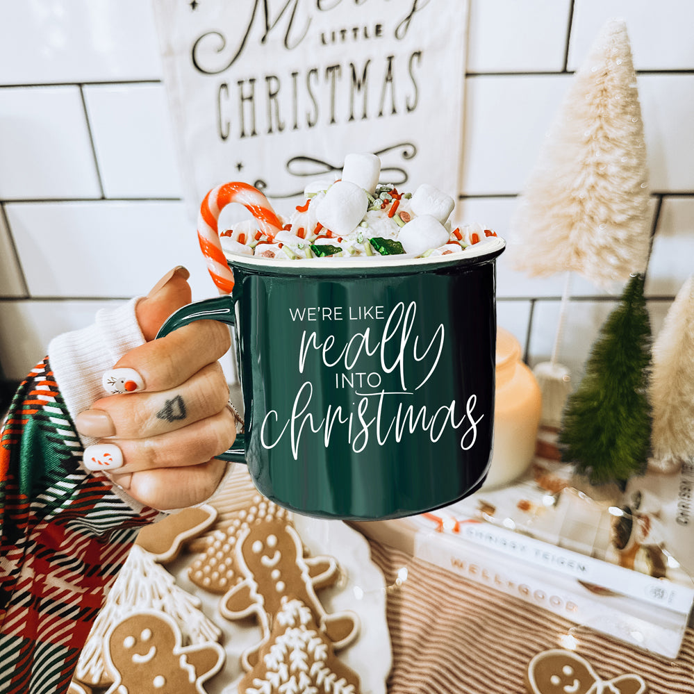 A vibrant red and green ceramic mug with white lettering, featuring a festive design on both sides, perfect for holiday drinks.