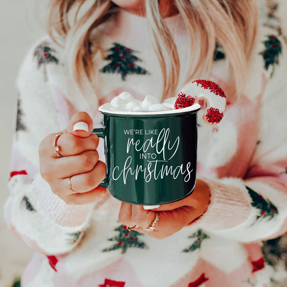 A vibrant red and green ceramic mug with white lettering, featuring a festive design on both sides, perfect for holiday drinks.