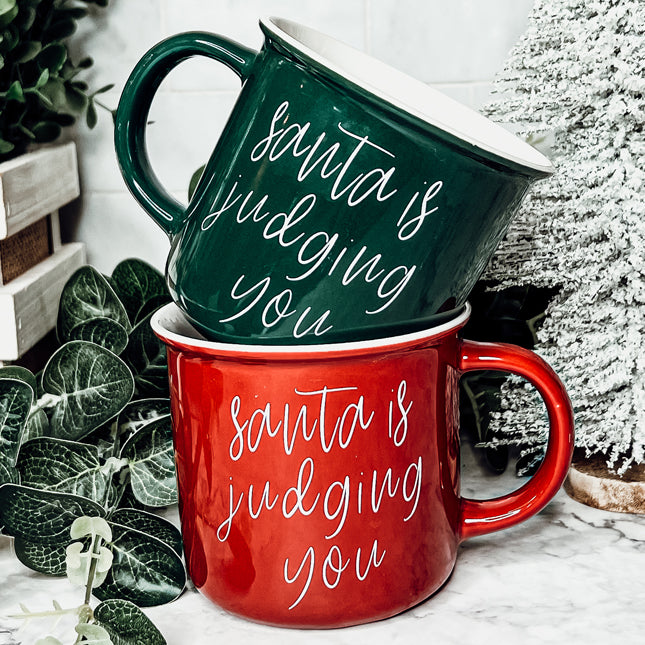 A festive ceramic mug featuring a humorous Santa design, available in red or green, perfect for holiday beverages.