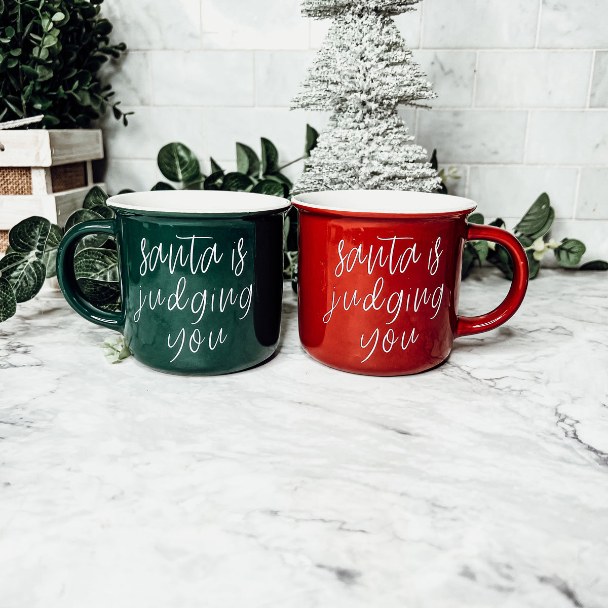 A festive ceramic mug featuring a humorous Santa design, available in red or green, perfect for holiday beverages.