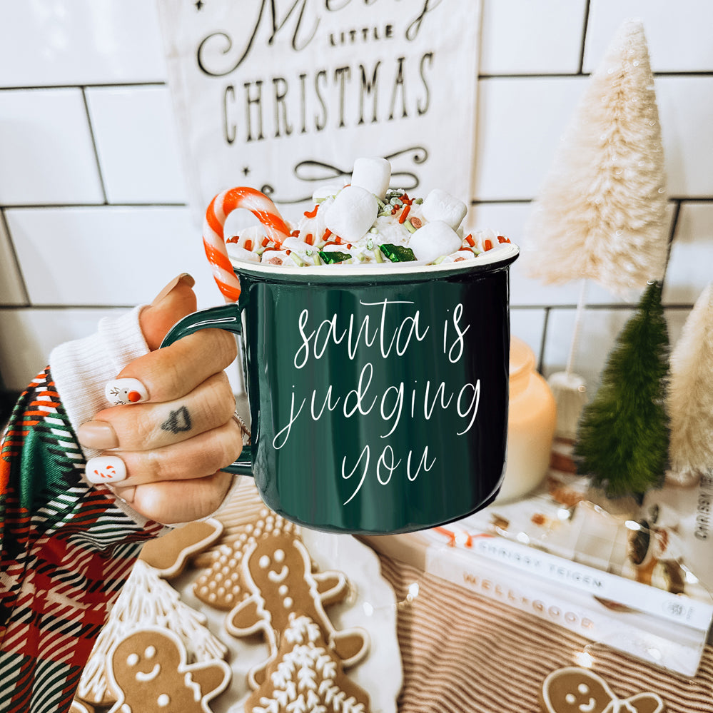 A festive ceramic mug featuring a humorous Santa design, available in red or green, perfect for holiday beverages.