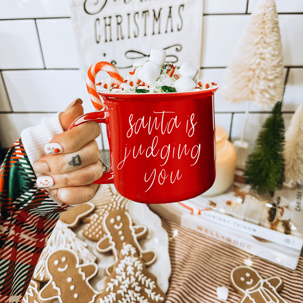 A festive ceramic mug featuring a humorous Santa design, available in red or green, perfect for holiday beverages.