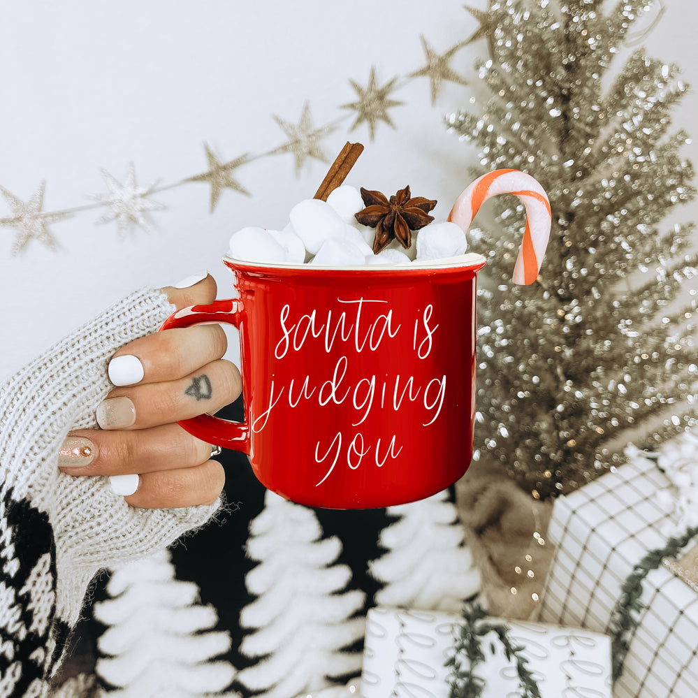 A festive ceramic mug featuring a humorous Santa design, available in red or green, perfect for holiday beverages.