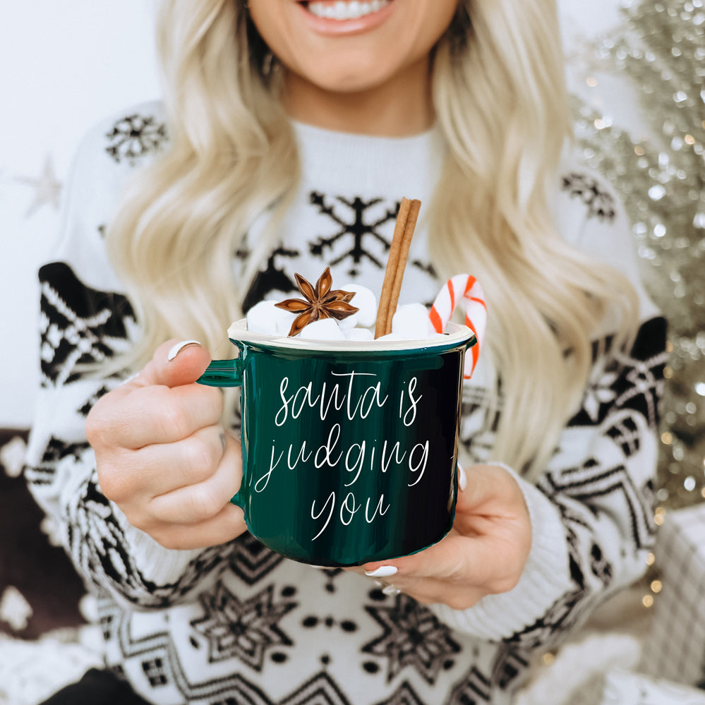 A festive ceramic mug featuring a humorous Santa design, available in red or green, perfect for holiday beverages.