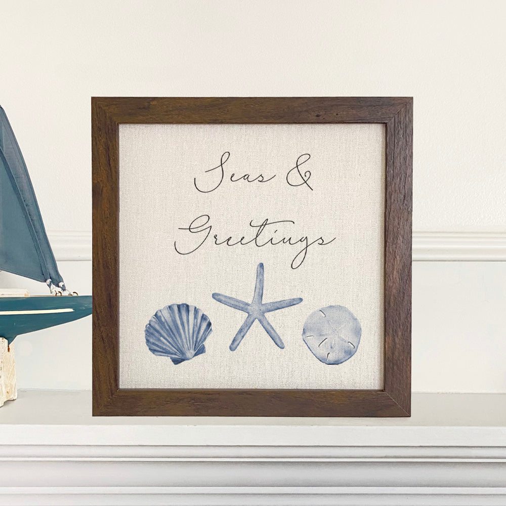 Seas & Greetings Framed Sign with a stylized wood frame, eco-friendly printing on a linen-look background.