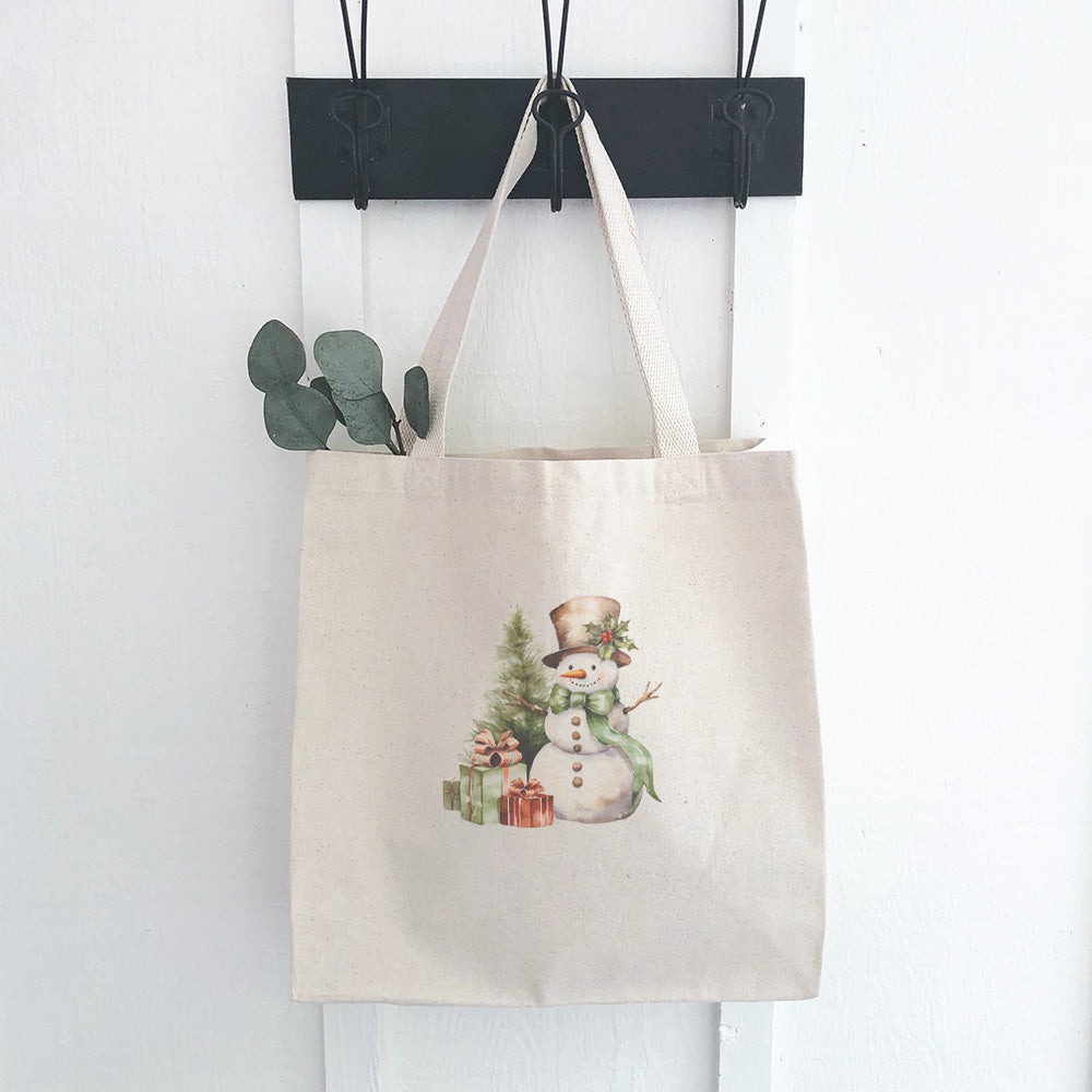 A festive canvas tote bag featuring a cheerful snowman surrounded by colorful presents, perfect for holiday shopping.