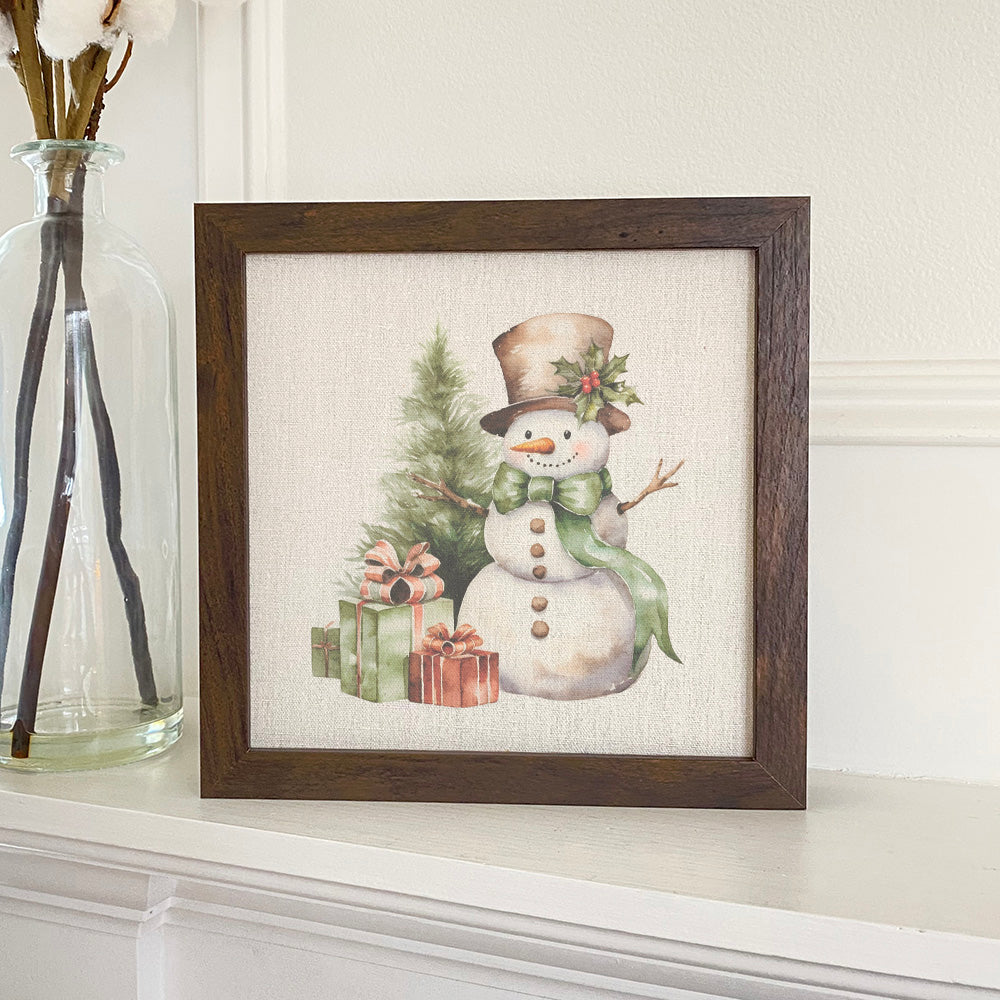 A charming framed sign featuring a snowman and presents, set in a rustic wood frame, perfect for holiday decor.