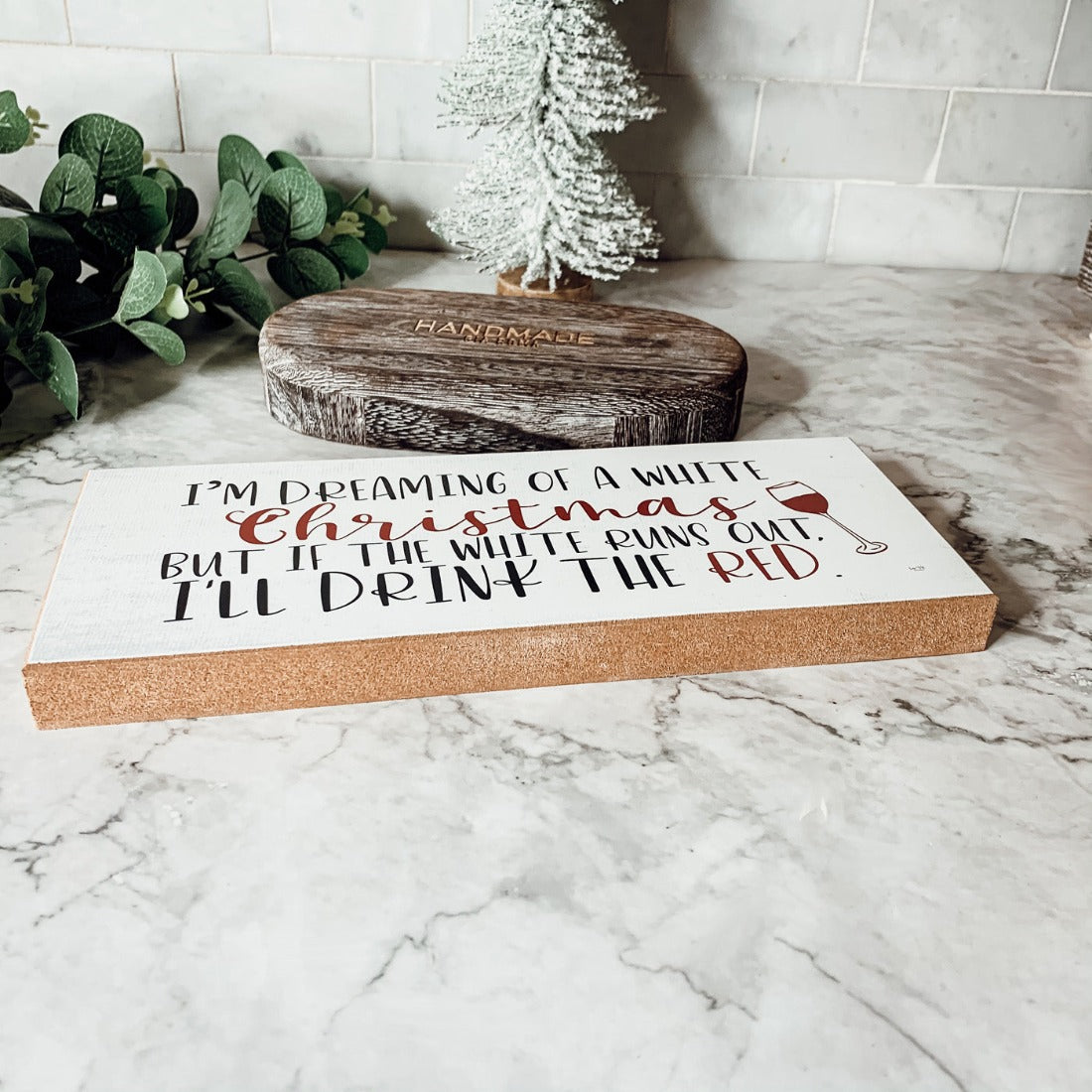 A handmade wooden sign featuring a humorous Christmas quote about wine, designed for festive decor.