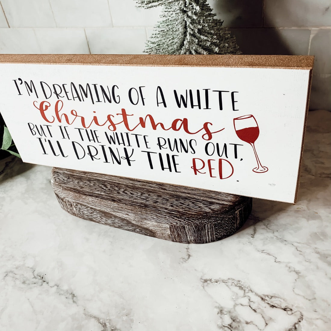 A handmade wooden sign featuring a humorous Christmas quote about wine, designed for festive decor.