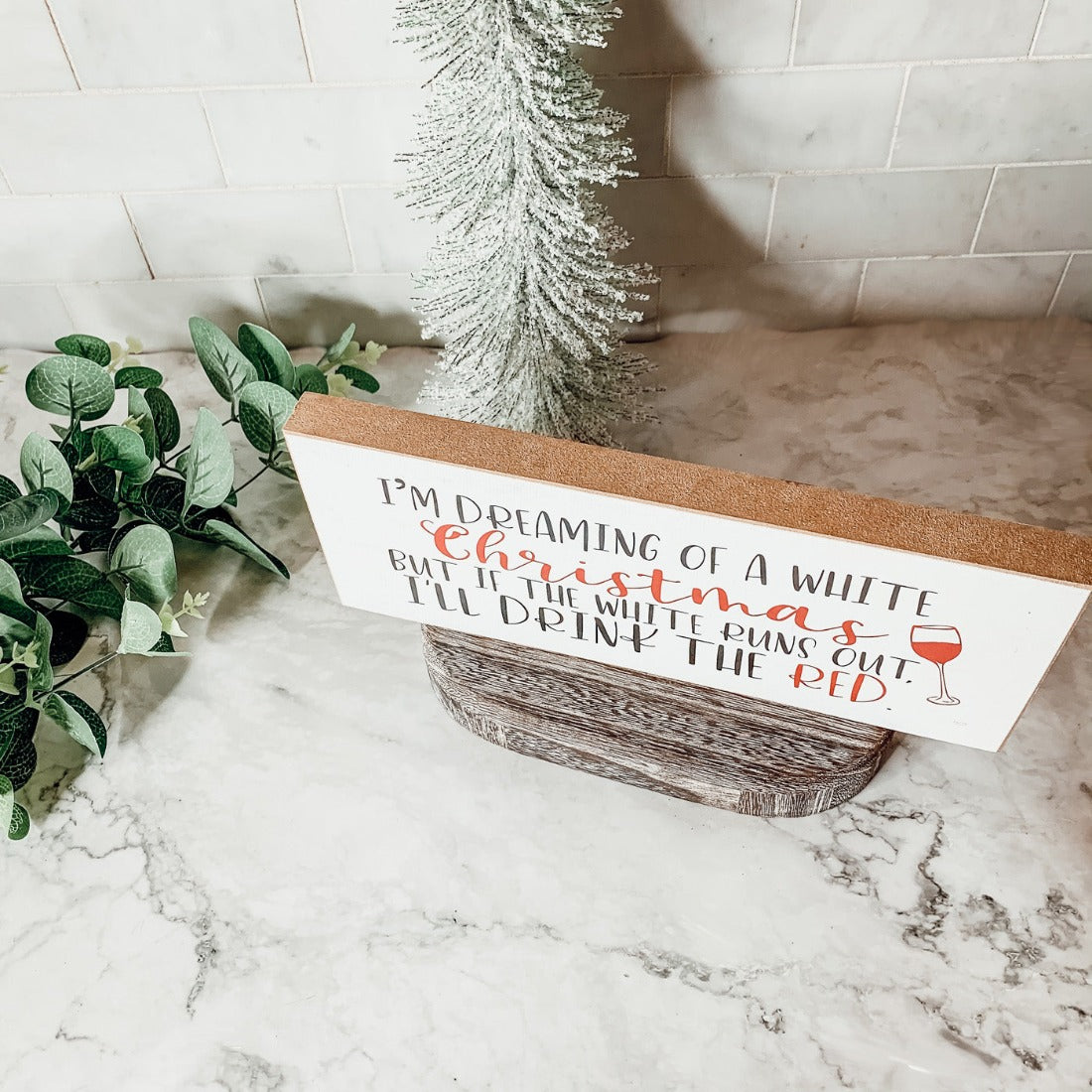 A handmade wooden sign featuring a humorous Christmas quote about wine, designed for festive decor.