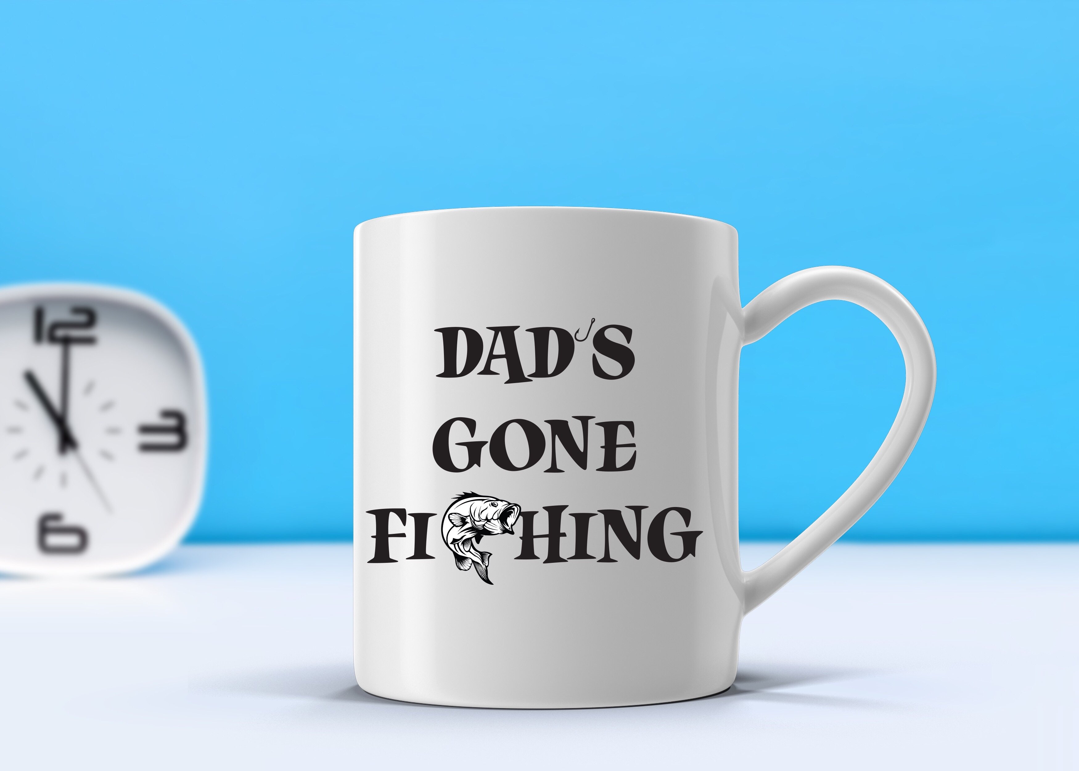 A glossy white ceramic mug with 'Dad’s Gone Fishing' printed on it, perfect for coffee or tea.