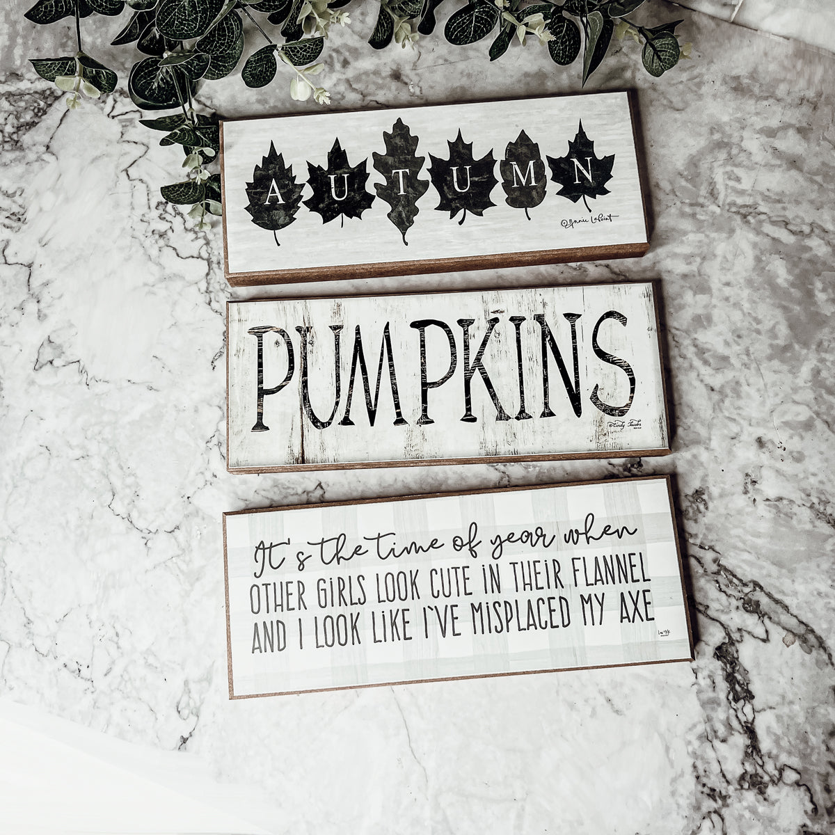 Rustic Autumn sign with off-white background and leaf designs, spelling 'Autumn' in elegant letters.