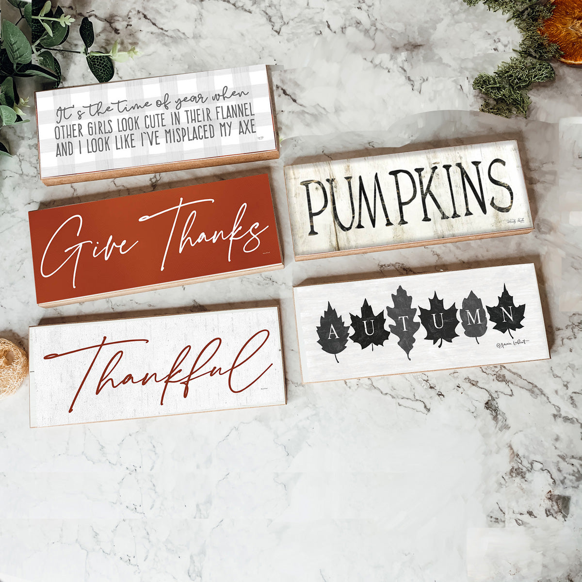 Rustic Autumn sign with off-white background and leaf designs, spelling 'Autumn' in elegant letters.