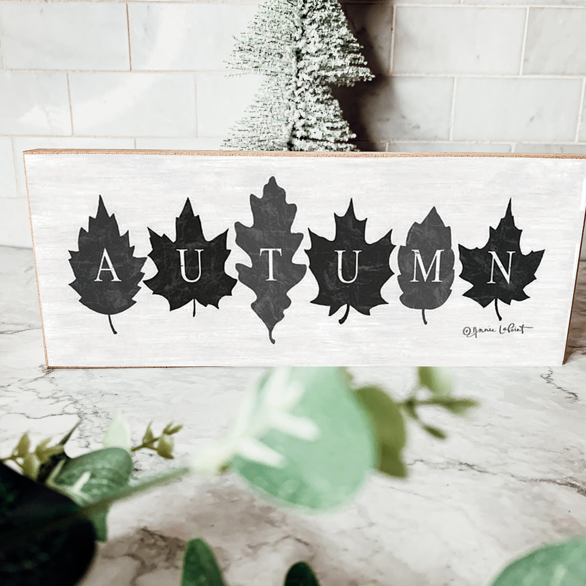 Rustic Autumn sign with off-white background and leaf designs, spelling 'Autumn' in elegant letters.