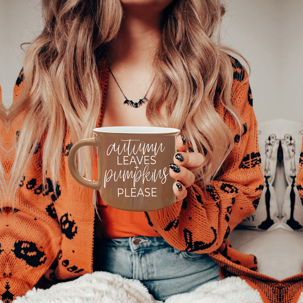 A ceramic campfire style mug featuring a neutral brown tone with white lettering that reads 'Autumn Leaves + Pumpkins Please', designed for fall.