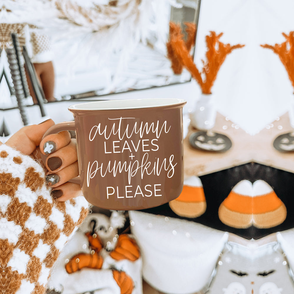 A ceramic campfire style mug featuring a neutral brown tone with white lettering that reads 'Autumn Leaves + Pumpkins Please', designed for fall.