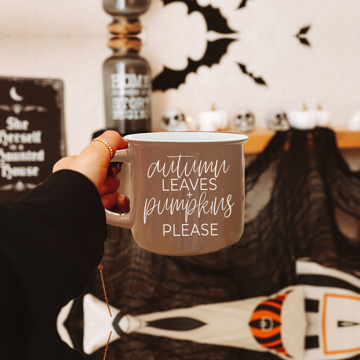 A ceramic campfire style mug featuring a neutral brown tone with white lettering that reads 'Autumn Leaves + Pumpkins Please', designed for fall.