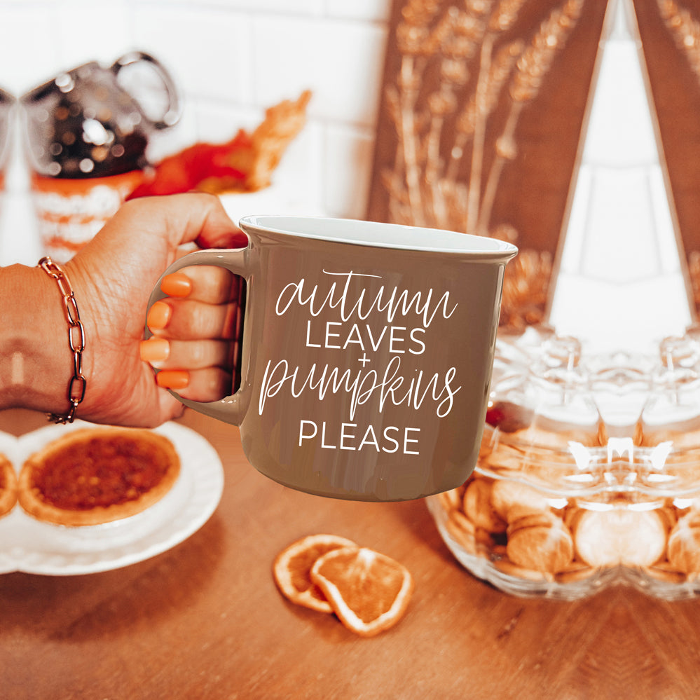 A ceramic campfire style mug featuring a neutral brown tone with white lettering that reads 'Autumn Leaves + Pumpkins Please', designed for fall.