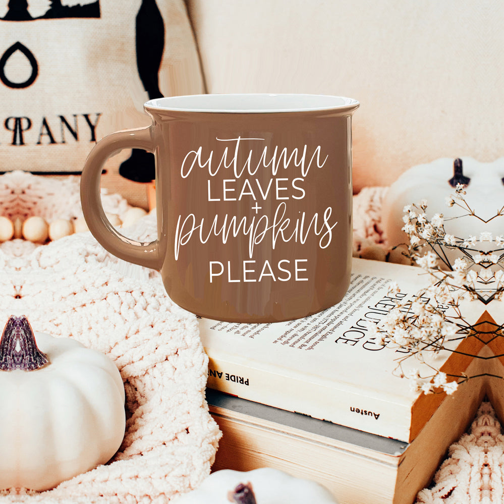 A ceramic campfire style mug featuring a neutral brown tone with white lettering that reads 'Autumn Leaves + Pumpkins Please', designed for fall.