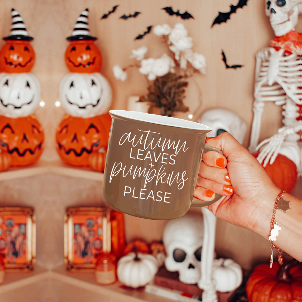 A ceramic campfire style mug featuring a neutral brown tone with white lettering that reads 'Autumn Leaves + Pumpkins Please', designed for fall.