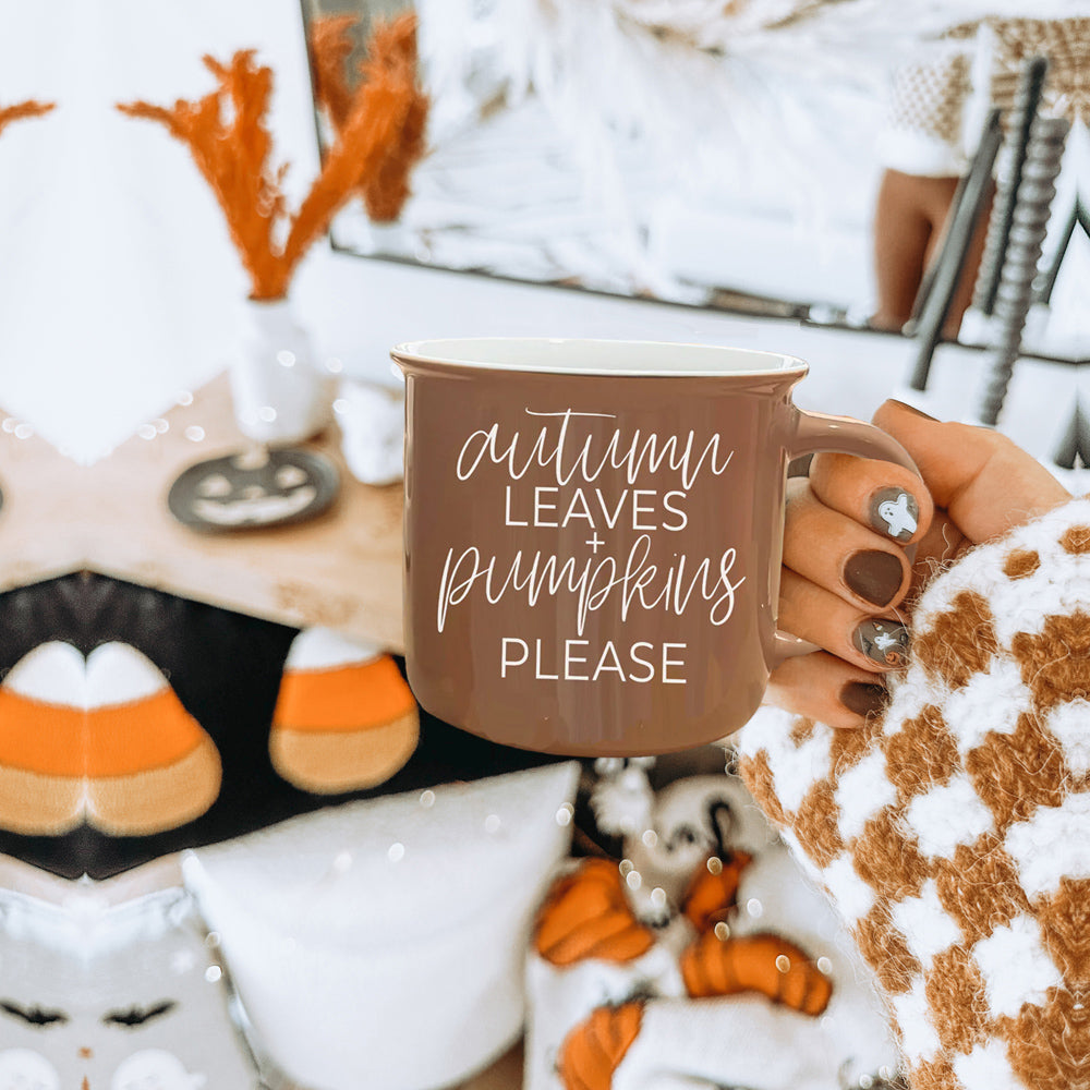 A ceramic campfire style mug featuring a neutral brown tone with white lettering that reads 'Autumn Leaves + Pumpkins Please', designed for fall.