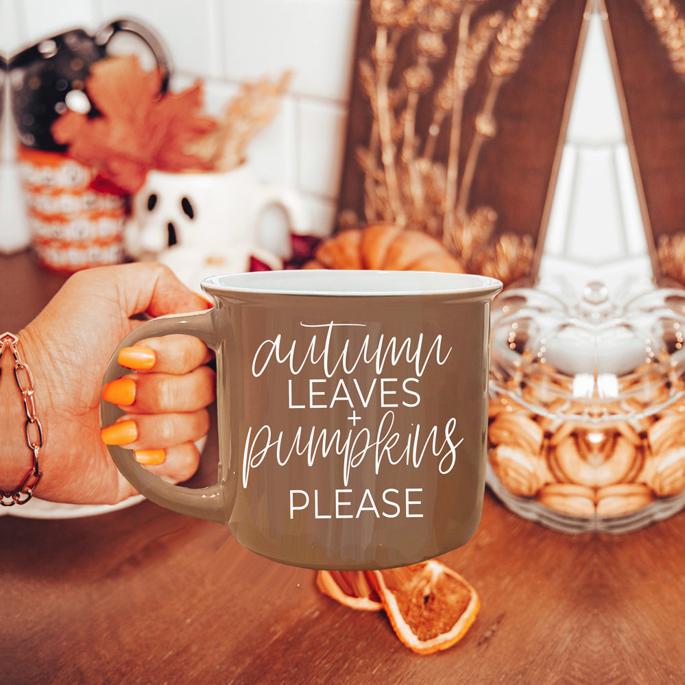 A ceramic campfire style mug featuring a neutral brown tone with white lettering that reads 'Autumn Leaves + Pumpkins Please', designed for fall.