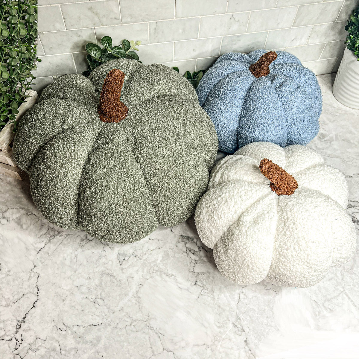 A collection of plush Blair Pumpkins in various colors including blue, gray, and orange, showcasing their soft texture and classic pumpkin shape.