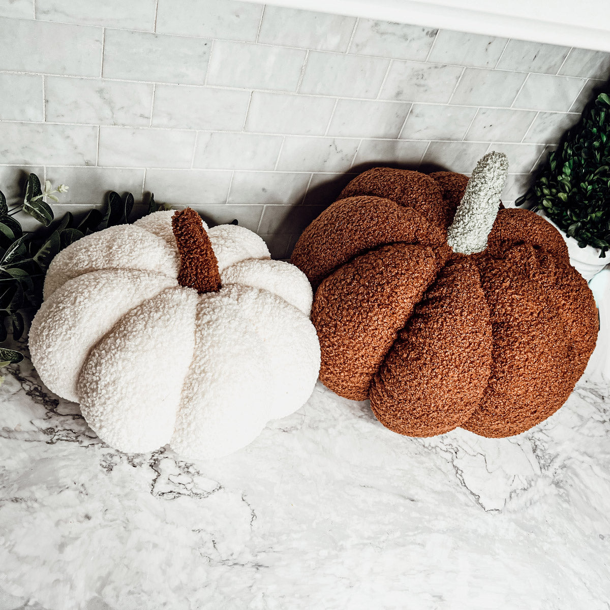 A collection of plush Blair Pumpkins in various colors including blue, gray, and orange, showcasing their soft texture and classic pumpkin shape.