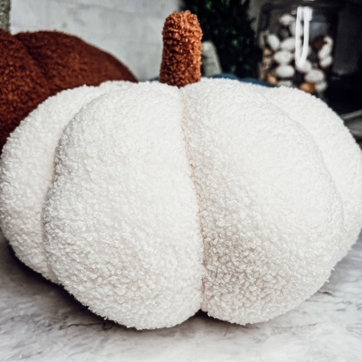 A collection of plush Blair Pumpkins in various colors including blue, gray, and orange, showcasing their soft texture and classic pumpkin shape.