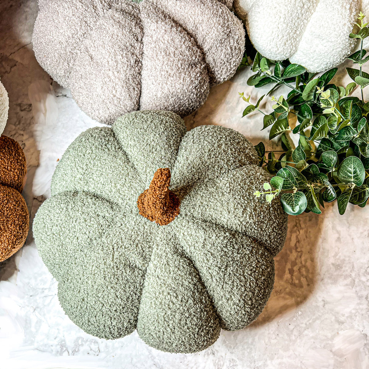 A collection of plush Blair Pumpkins in various colors including blue, gray, and orange, showcasing their soft texture and classic pumpkin shape.