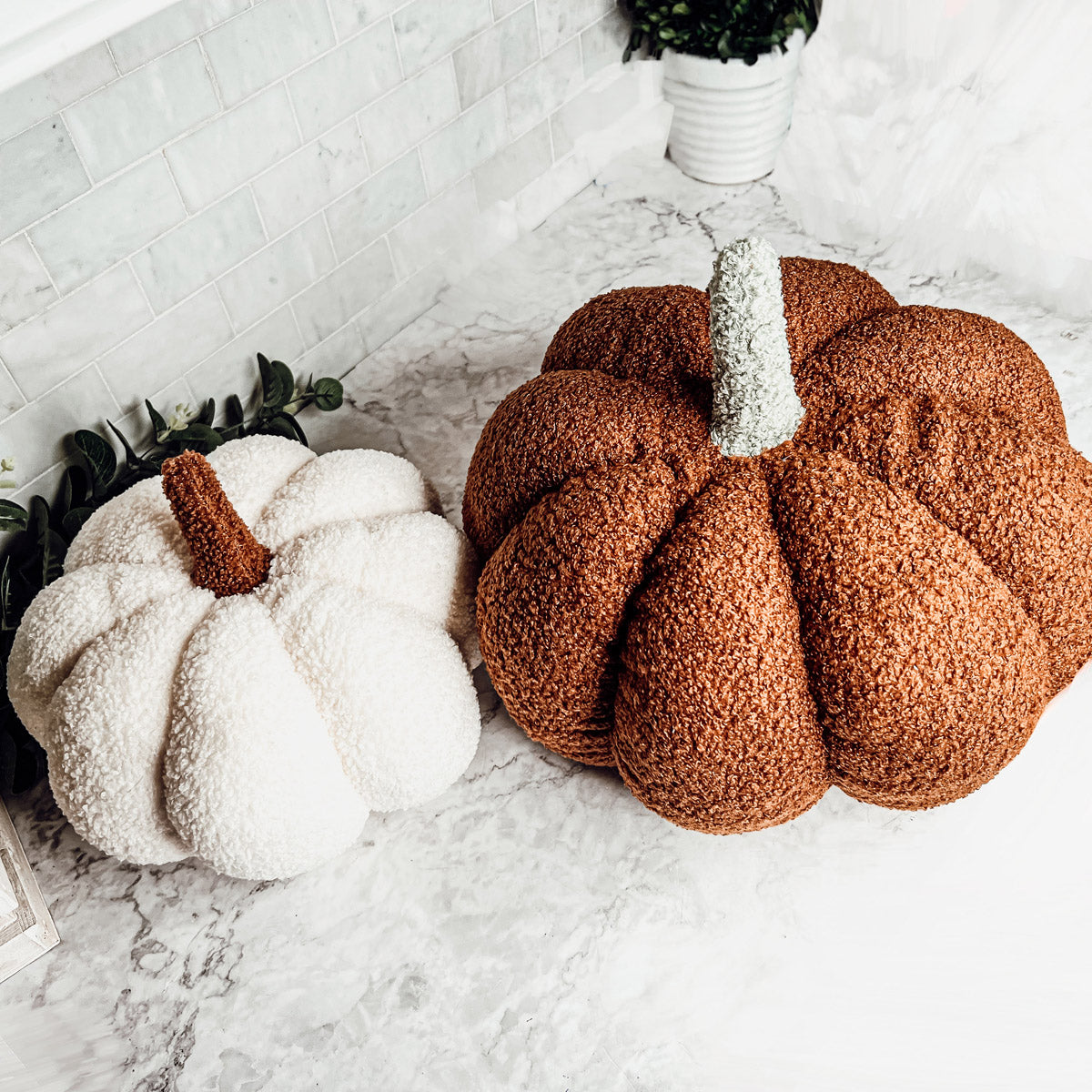 A collection of plush Blair Pumpkins in various colors including blue, gray, and orange, showcasing their soft texture and classic pumpkin shape.