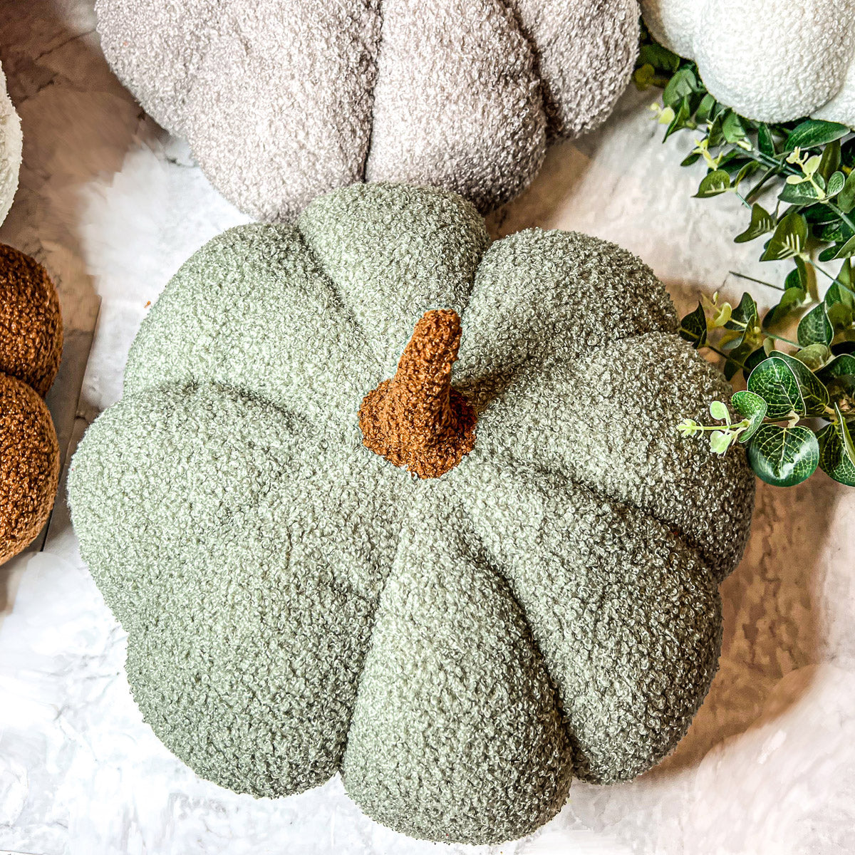 A collection of plush Blair Pumpkins in various colors including blue, gray, and orange, showcasing their soft texture and classic pumpkin shape.